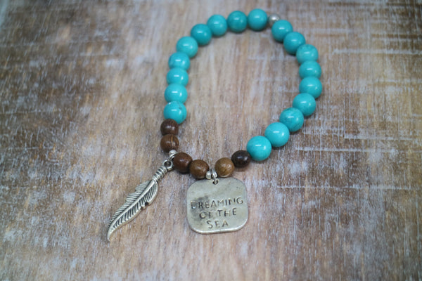 Load image into Gallery viewer, Turquoise and wood beaded bracelet with rustic silver &#39;dreaming of the sea&#39; charm and boho feather charm
